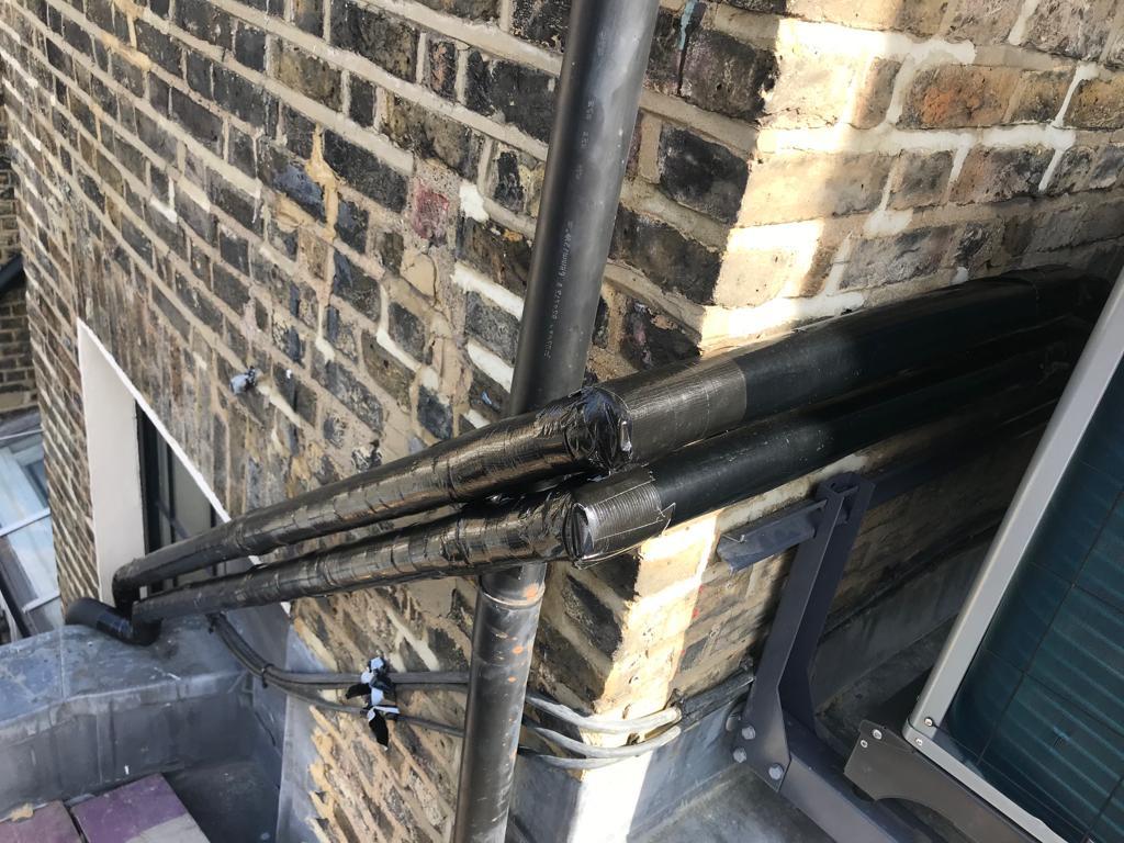 Insulated pipework on London brick facade